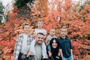A group poses in front of vibrant orange autumn trees during fall.