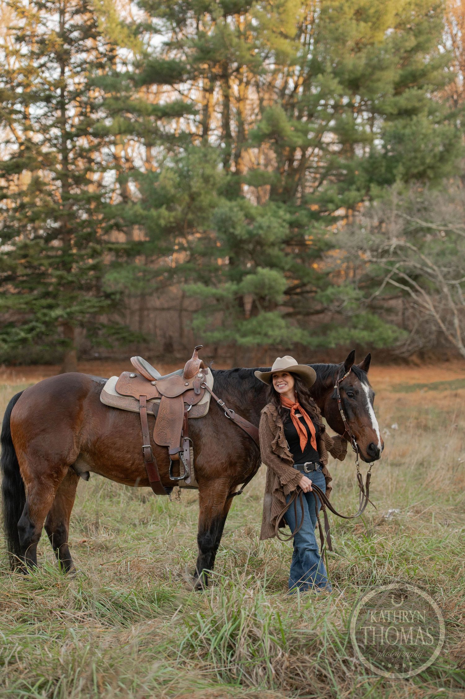 A horse and rider pause in a scenic wooded clearing with evergreen trees in the background.