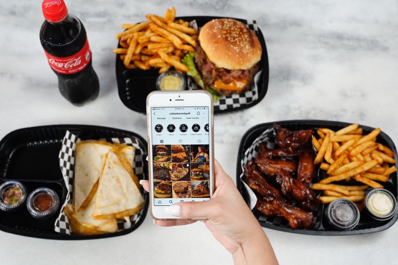 Fast food meal with burger, fries, and phone displaying food delivery app.