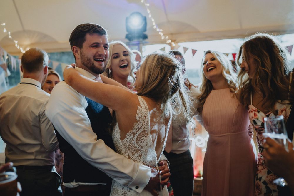 A joyful celebration of guests dancing and laughing together at a wedding reception.