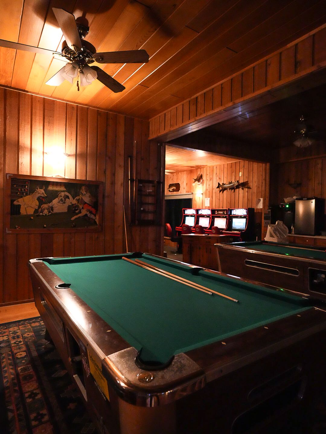 Pool table in a wood-paneled game room with ambient lighting.