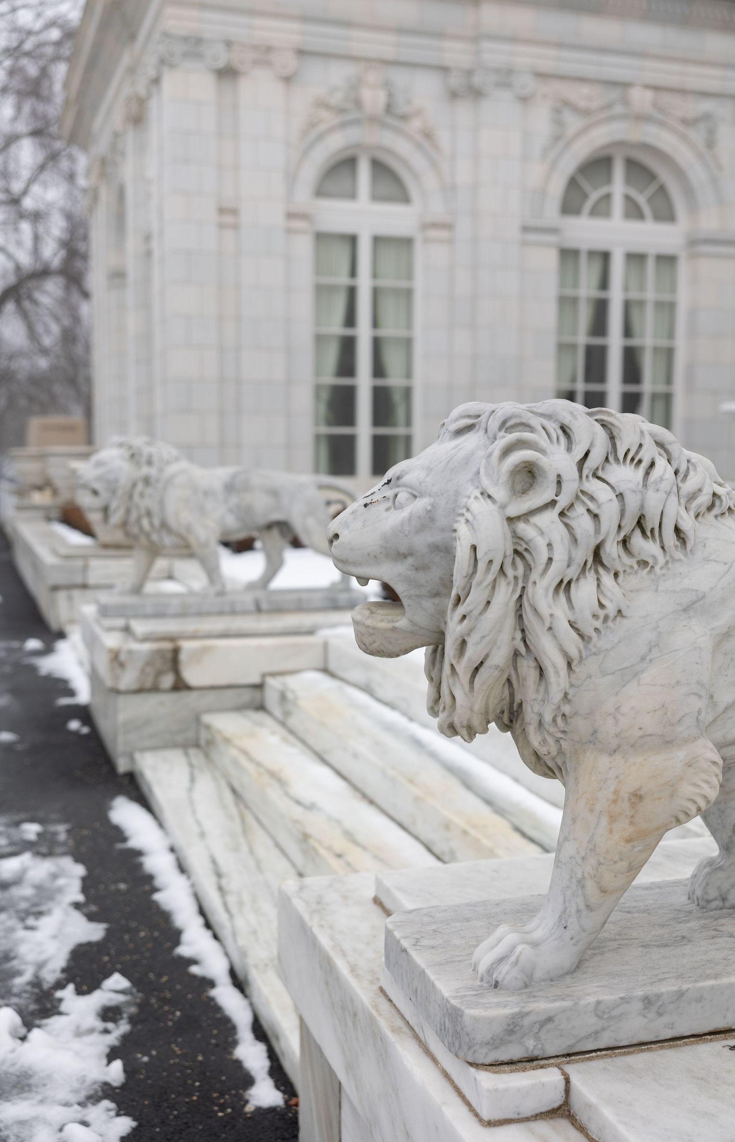 White stone lion sculptures guard a neoclassical building entrance with arched windows. Rosehill Mansion, Newport Rhode Island