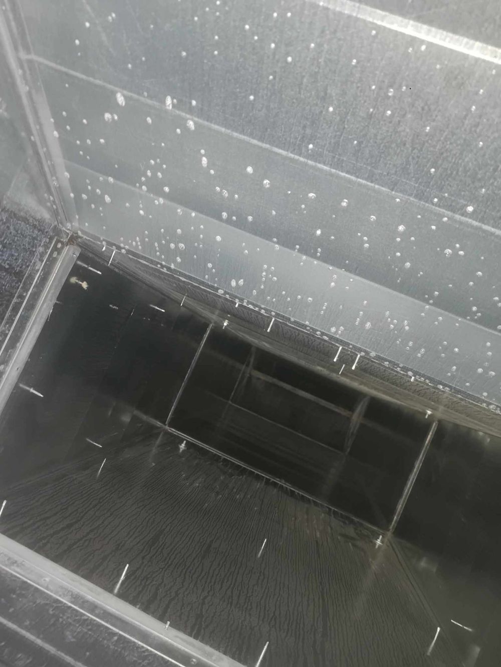 Close-up of water droplets on metal surface inside industrial ventilation system.