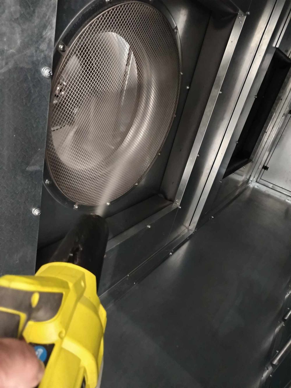 Close-up of industrial ventilation system with yellow inspection tool.