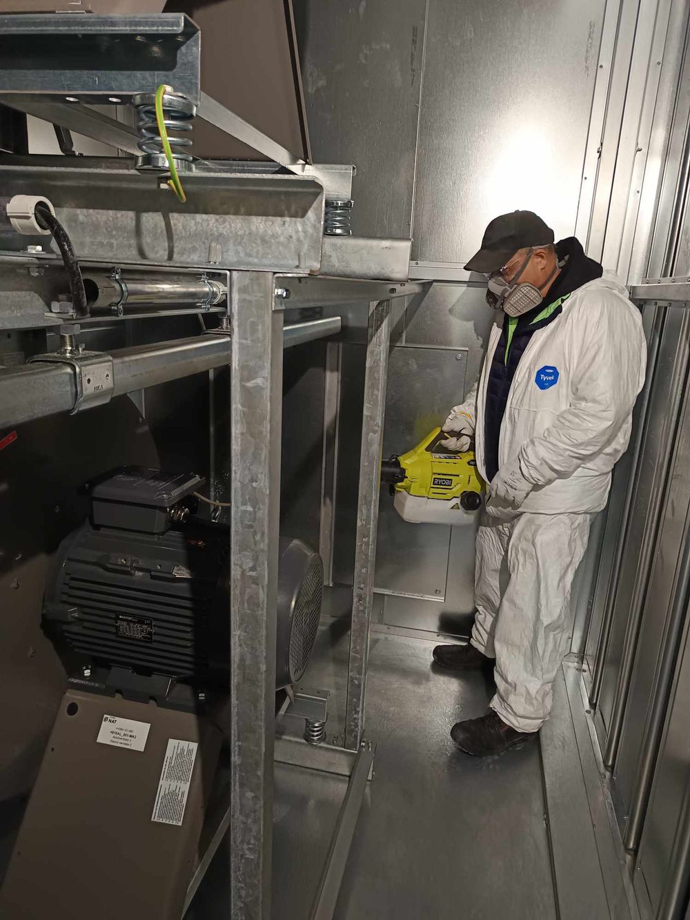 Maintenance worker in protective gear inspecting industrial equipment.