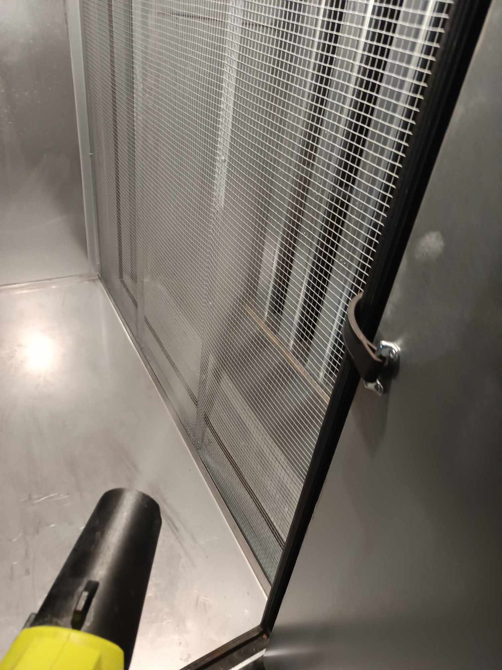 Industrial ventilation system with mesh screen being inspected.