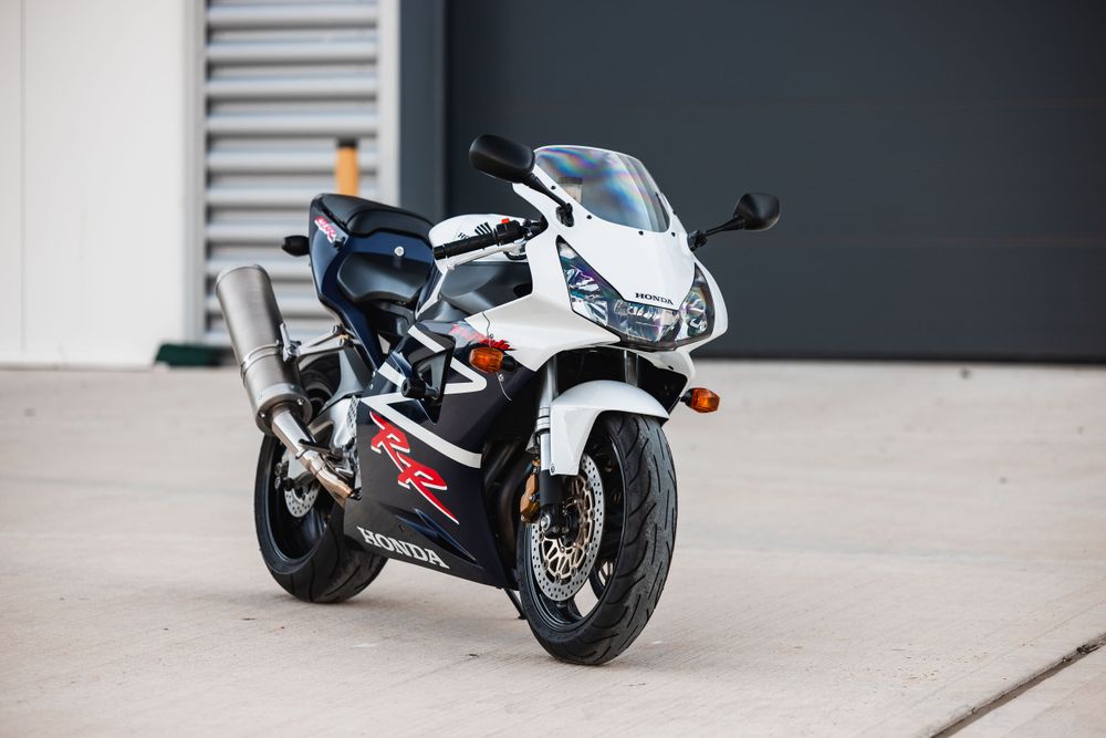 Sleek white and blue Honda CBR RR sportbike parked on concrete near a garage door.