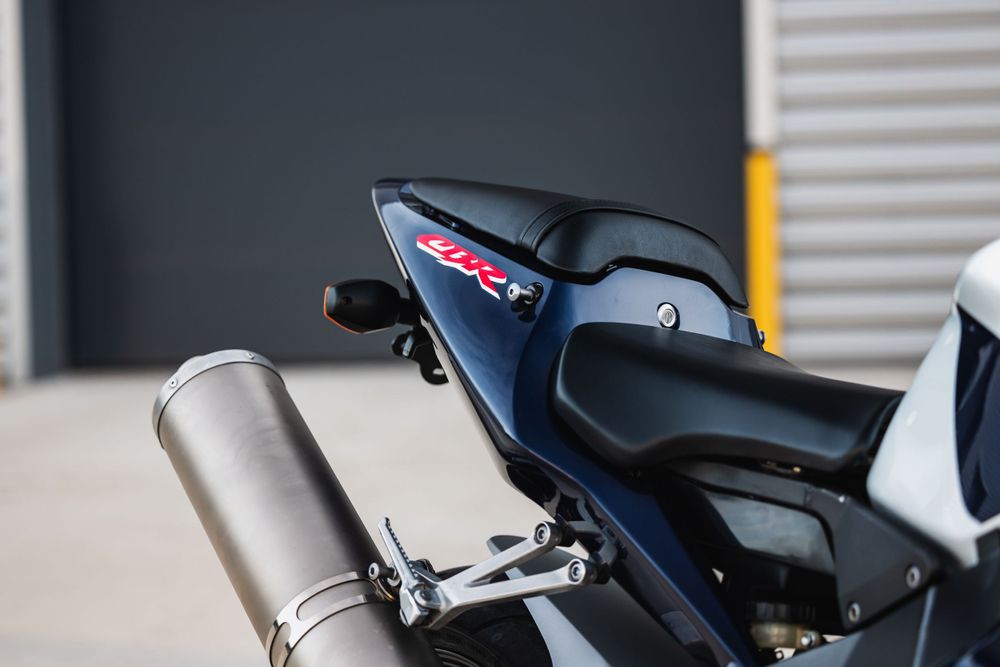 Close-up view of a motorcycle's tail section with a sleek black seat and silver exhaust pipe mounted to the side.