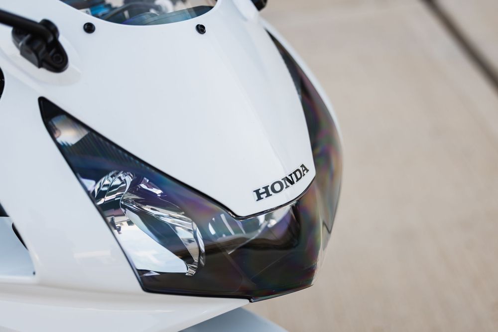 Close-up view of a white Honda motorcycle front fairing with headlight and windshield details.