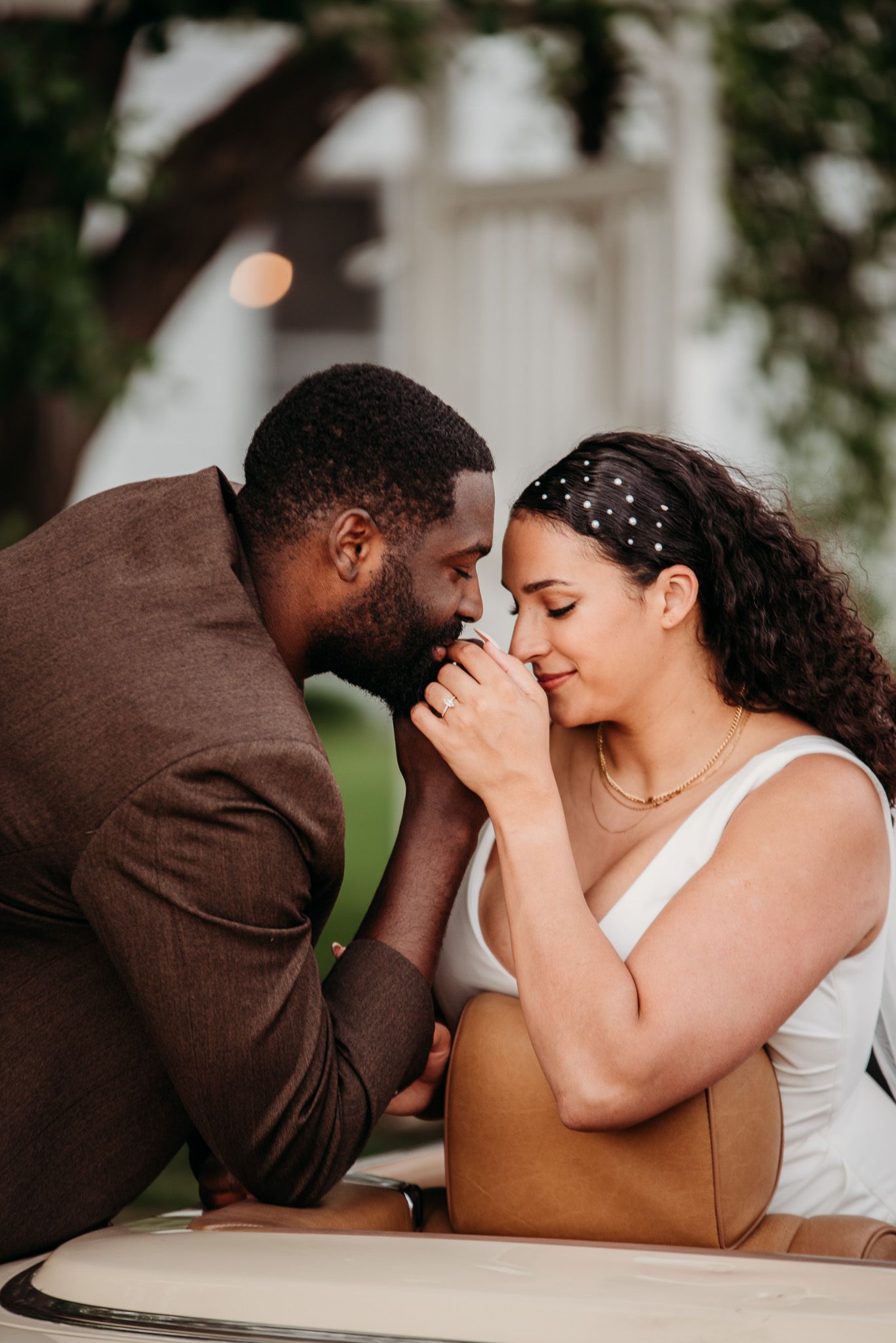 Intimate moment between newlyweds sharing a tender moment in convertible car.