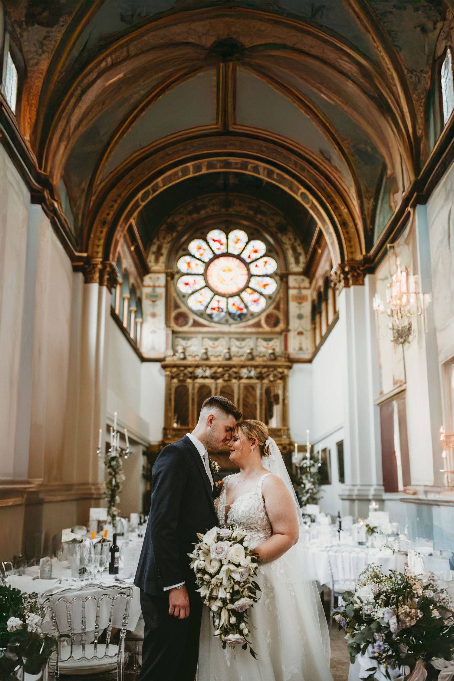 Wedding ceremony in a grand cathedral with vaulted ceilings and ornate rose window. De Vere Beaumont