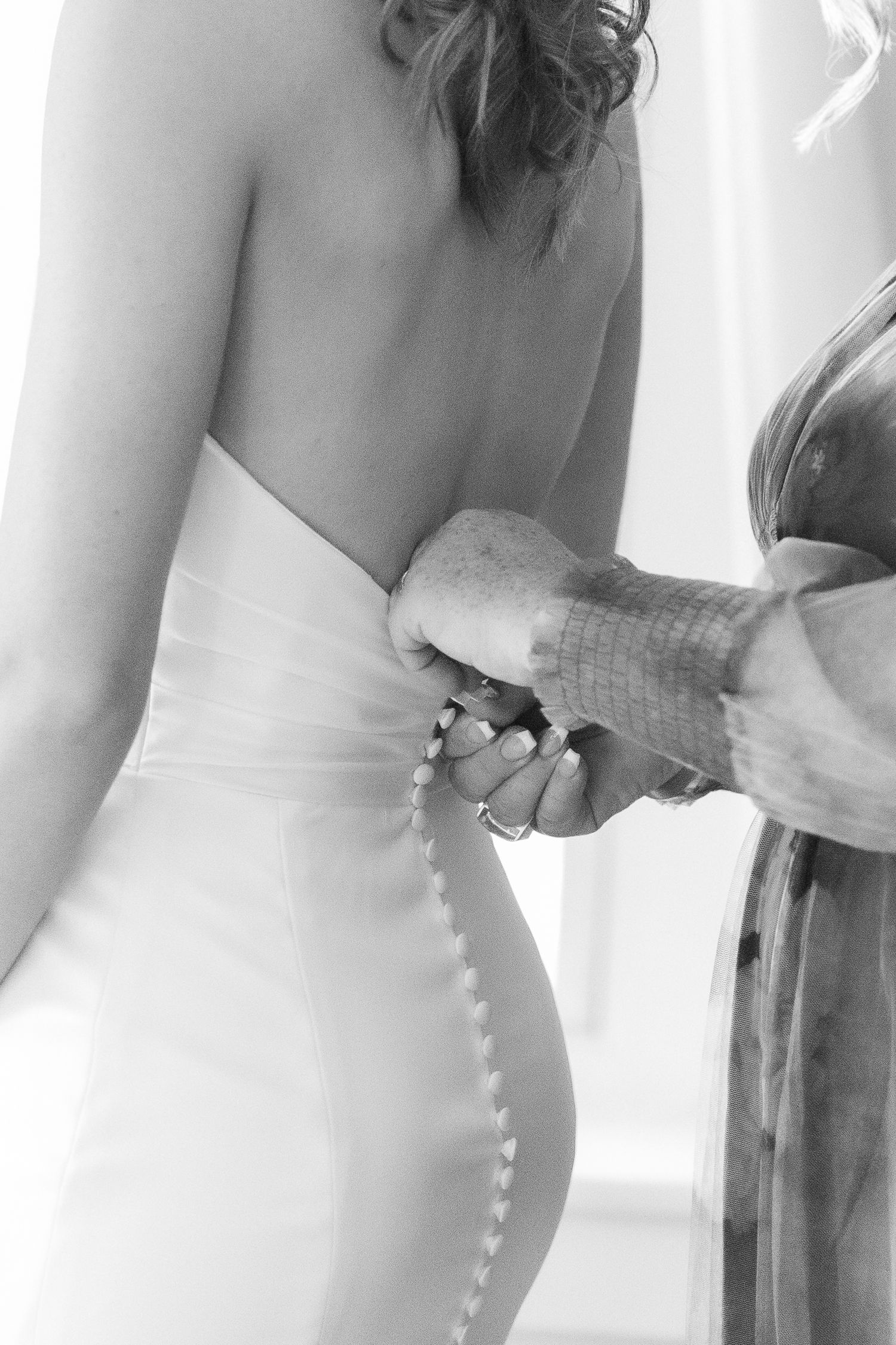 Detail shot of wedding dress buttons trailing down the back of an elegant white gown.