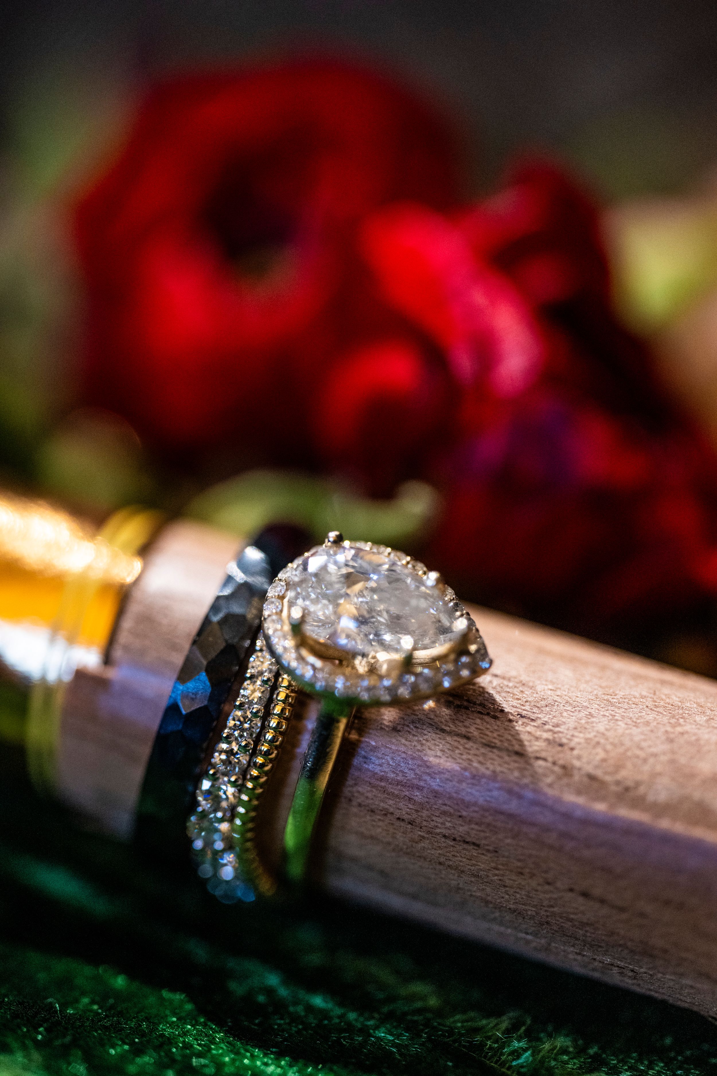 Diamond engagement ring displayed with red roses in dramatic lighting.