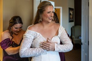 A bride getting ready in a lace long-sleeve wedding dress.