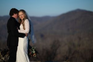 Couple embraces on mountain overlook during winter wedding photoshoot.