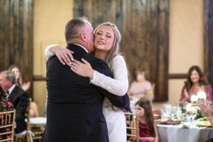 Dancing couple embraces during wedding reception in elegant ballroom.