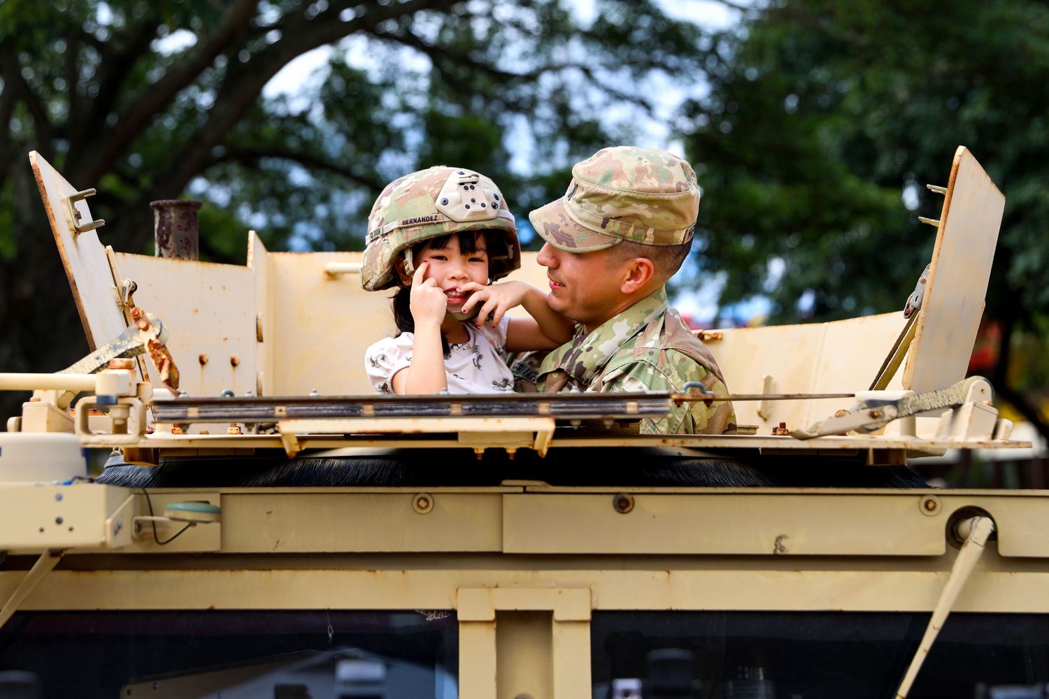 U.S. Army soldier holding child on top of vehicle — heartfelt military family moment captured in Hawaii by Live Tribe Media.