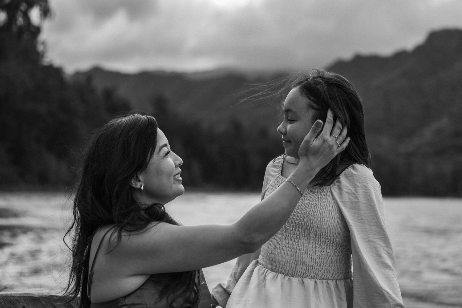 Mom holding daughter’s face with Hawaiian mountains in the background — tender family photo by Live Tribe Media.