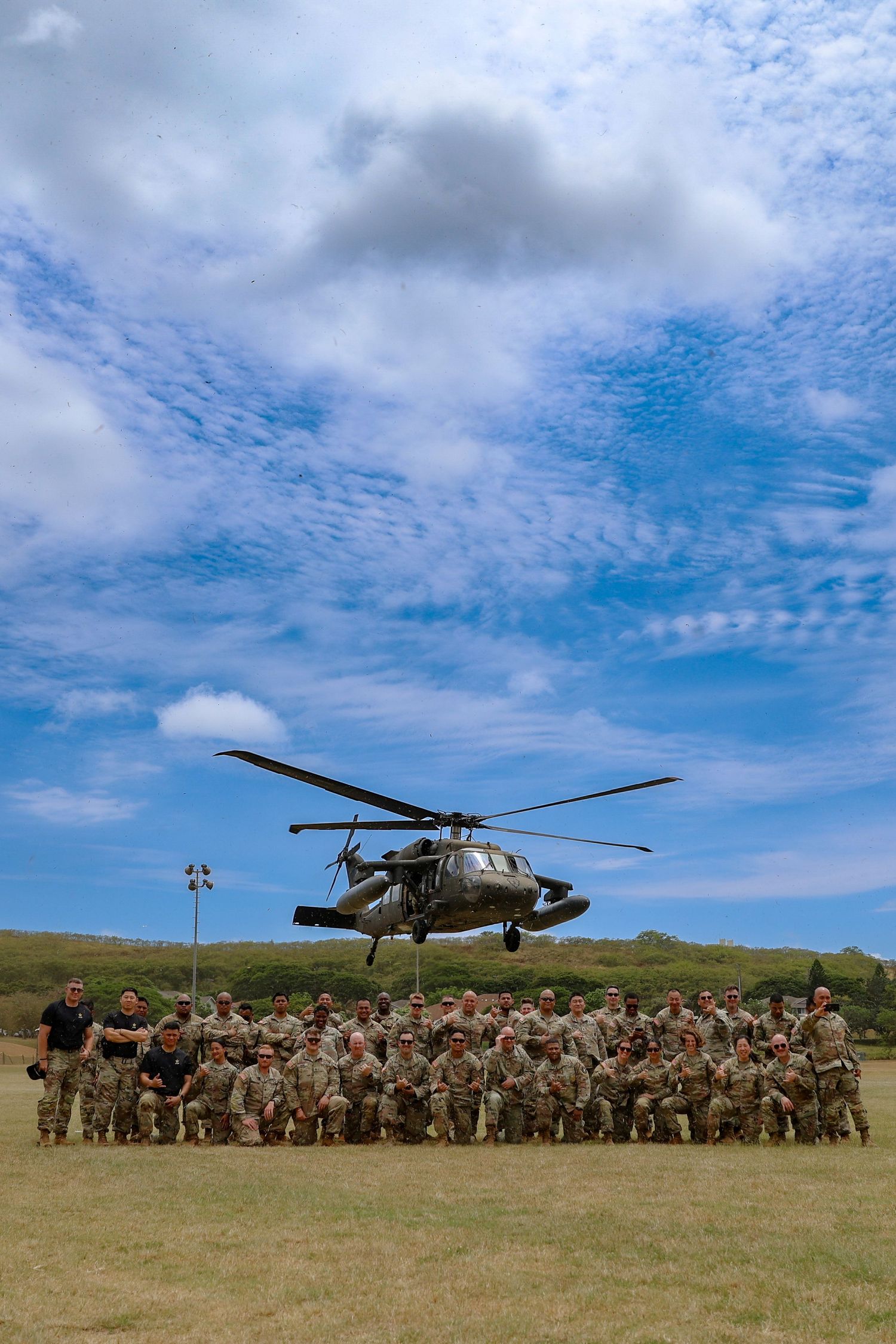 Group of U.S. Army soldiers on ground with helicopter hovering overhead — Oahu military photo by Live Tribe Media.