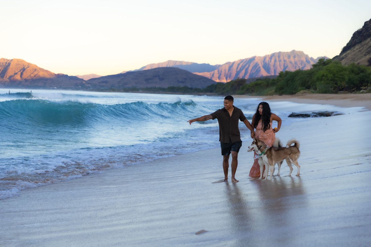 Couple walking with their dogs along the beach at sunrise — candid Hawaii lifestyle session by Live Tribe Media.
