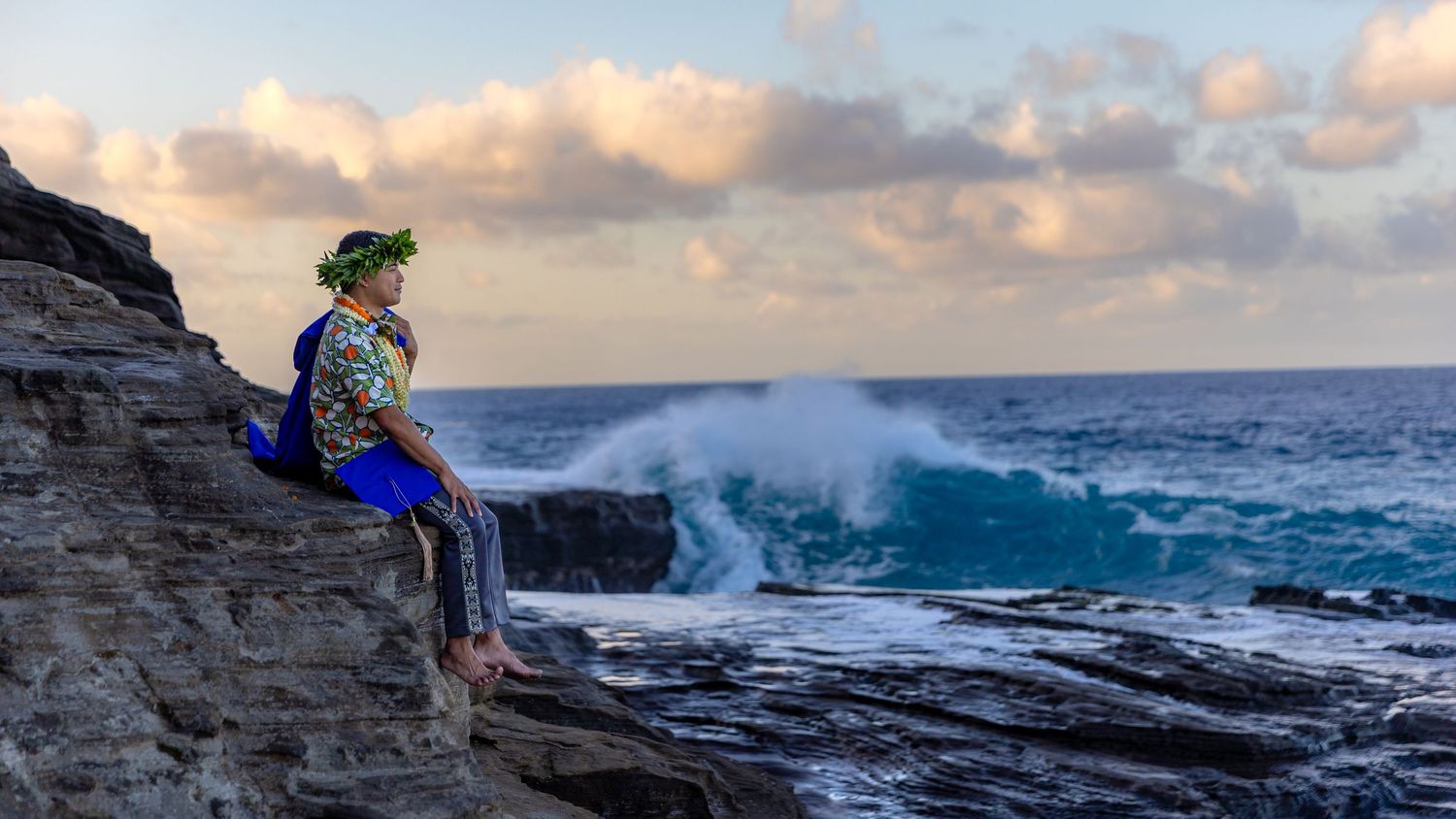 Senior graduate at China Walls during sunrise, waves crashing behind him — Oahu graduation photo by Live Tribe Media.