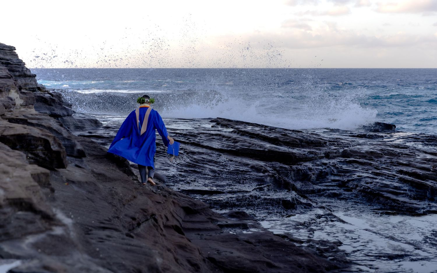 Male graduate in full cap and gown walking toward the ocean at China Walls — Hawaii lifestyle photo by Live Tribe Media.