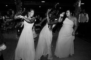 Wedding party dances together during evening reception in dark lighting.
