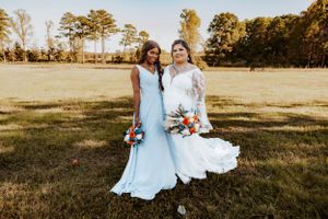 Wedding party poses in an open field during golden hour with trees in background.