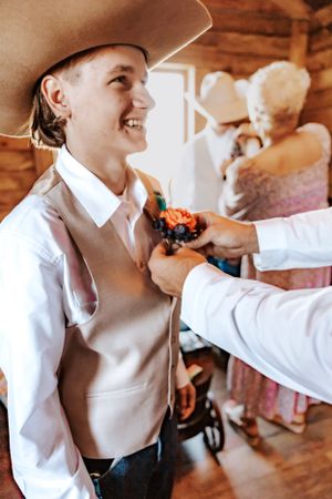 Wedding party members share joyful moments during preparation in a rustic indoor setting.