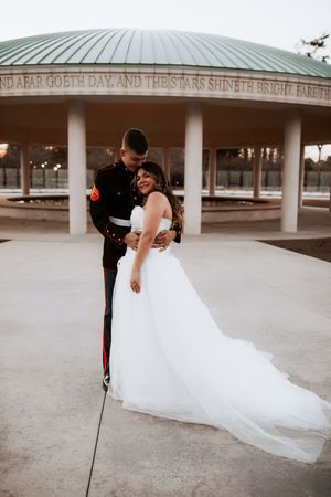 Romantic wedding portraits under covered pavilion with flowing white dress train.