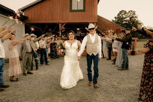 Wedding celebration outside rustic brown barn with guests forming reception line.