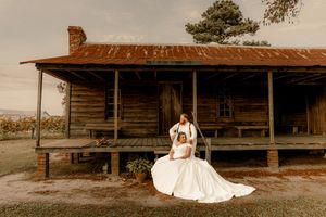 A rustic wooden barn venue with a covered porch area set against a natural outdoor backdrop during golden hour.