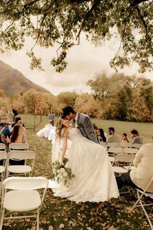 A romantic wedding ceremony moment in an outdoor mountain setting with white chairs and fall foliage.