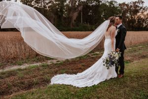 Long flowing wedding veil catches the breeze during outdoor portrait session.