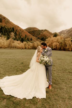 Newlyweds share romantic moments in a mountain valley with dramatic autumn scenery.