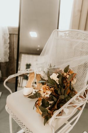 White metal outdoor chairs with dried floral arrangements create an elegant vintage wedding decor setting.