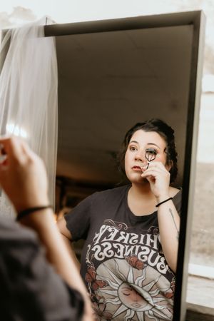 A sequence of photos shows someone in a graphic t-shirt applying eye makeup in natural window lighting.