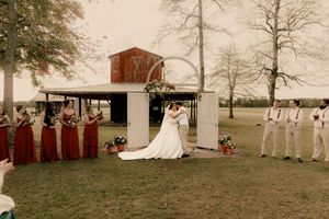 A panoramic view of a rustic red barn and white tent setup in a pastoral countryside setting during autumn.