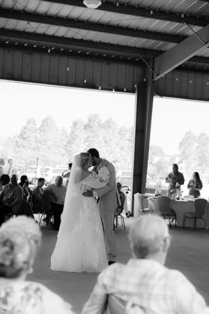 Black and white photo of a bride and groom sharing their first dance at a wedding reception in an open-air venue.