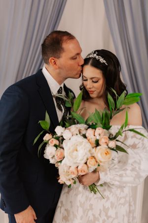 Romantic wedding portrait setup with peach roses and flowing white gown.