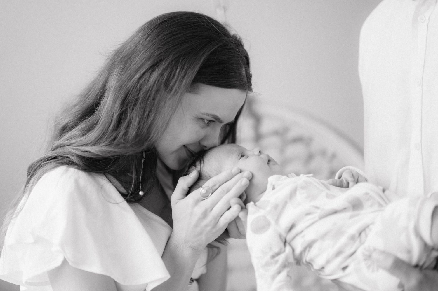 A tender black and white moment captured between a mother and newborn baby wrapped in soft blankets.