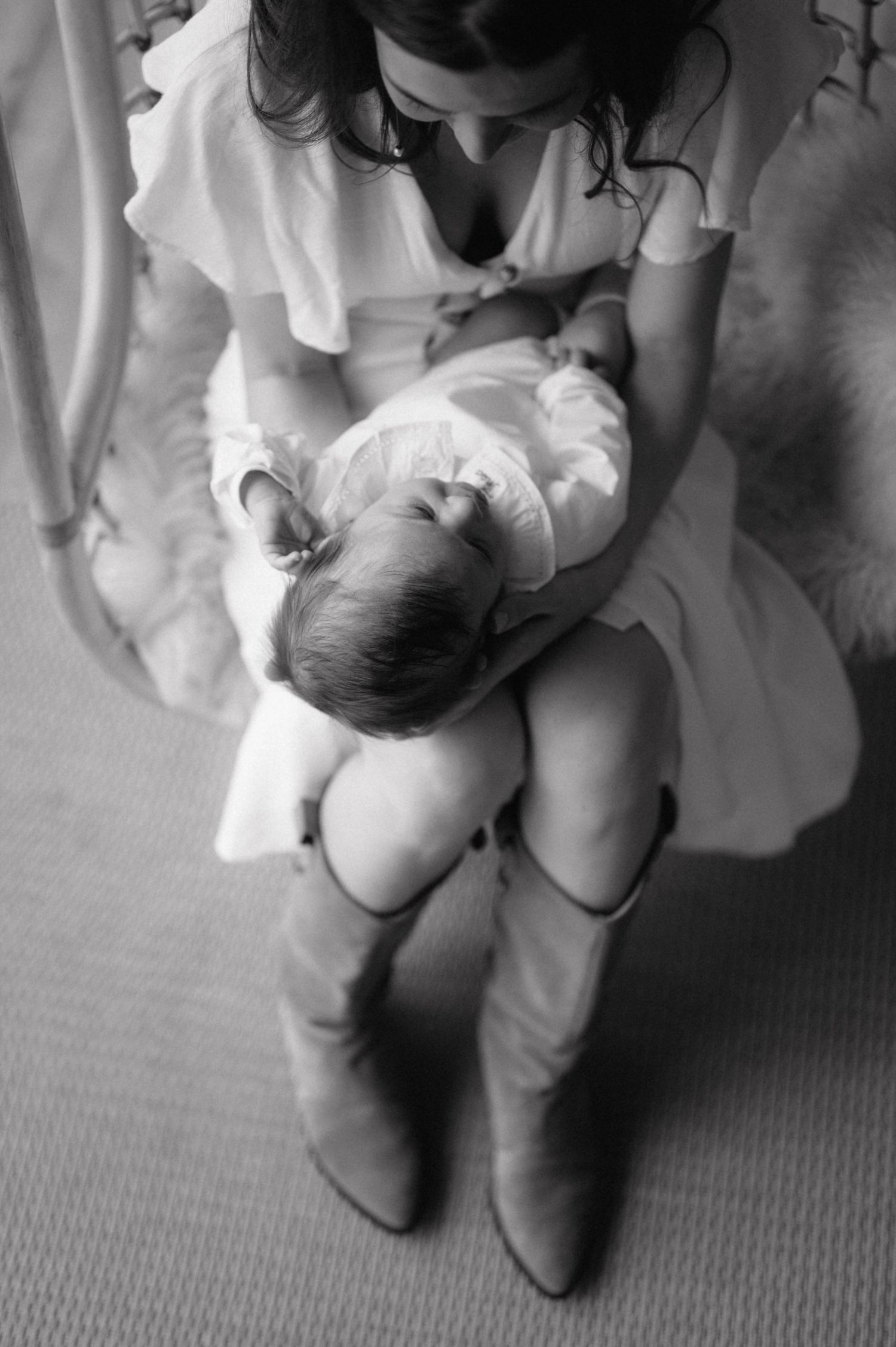 A tender black and white photograph shows a caregiver in white cradling a sleeping infant on their lap.