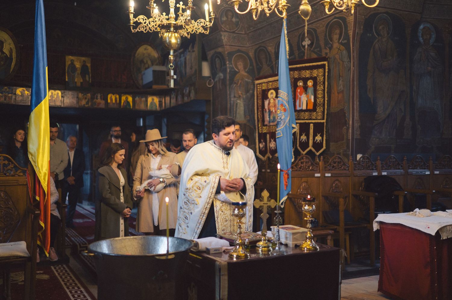 Orthodox clergy perform a religious ceremony at an altar inside a traditional Eastern church with ornate icons and candles.