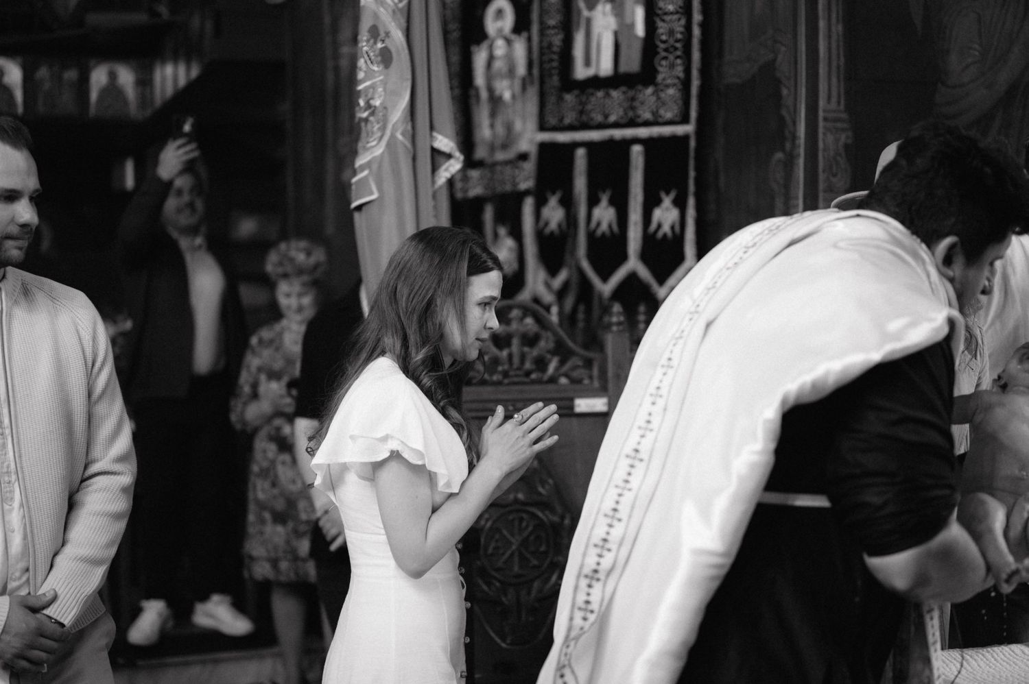 A person in white clothing stands beside a someone wearing religious robes during what appears to be a church ceremony.