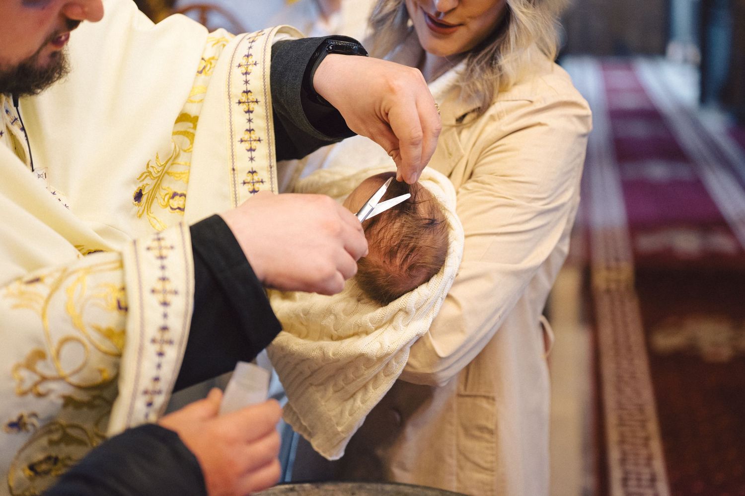 Orthodox Christian baptism ceremony showing hands performing ritual washing and blessing of an infant.