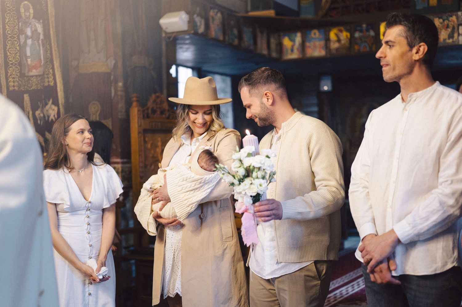 A small group of people dressed in light-colored attire gather together in what appears to be a rustic indoor setting.