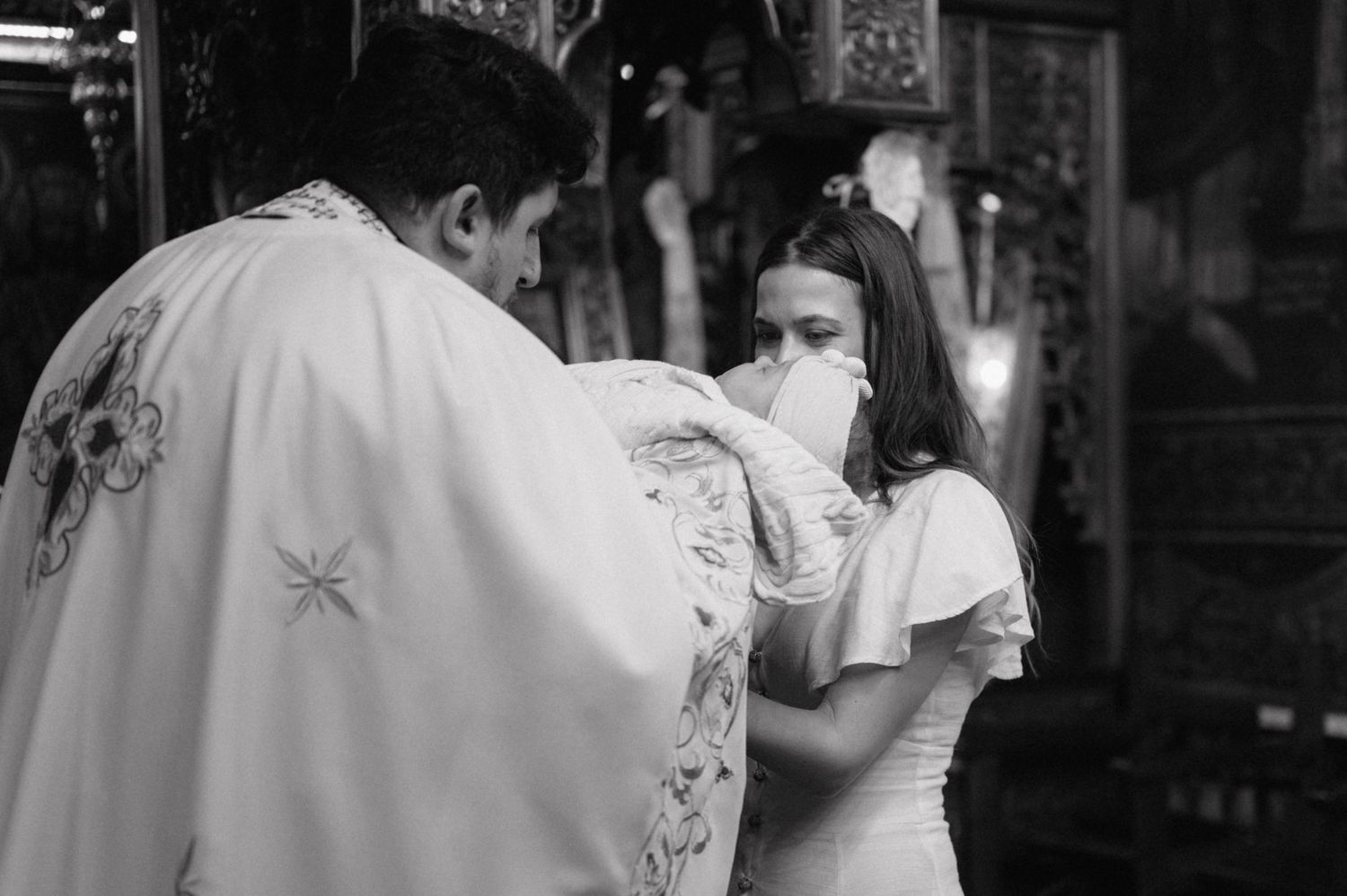 A black and white photograph showing a traditional Orthodox Christian communion ritual in a church interior.