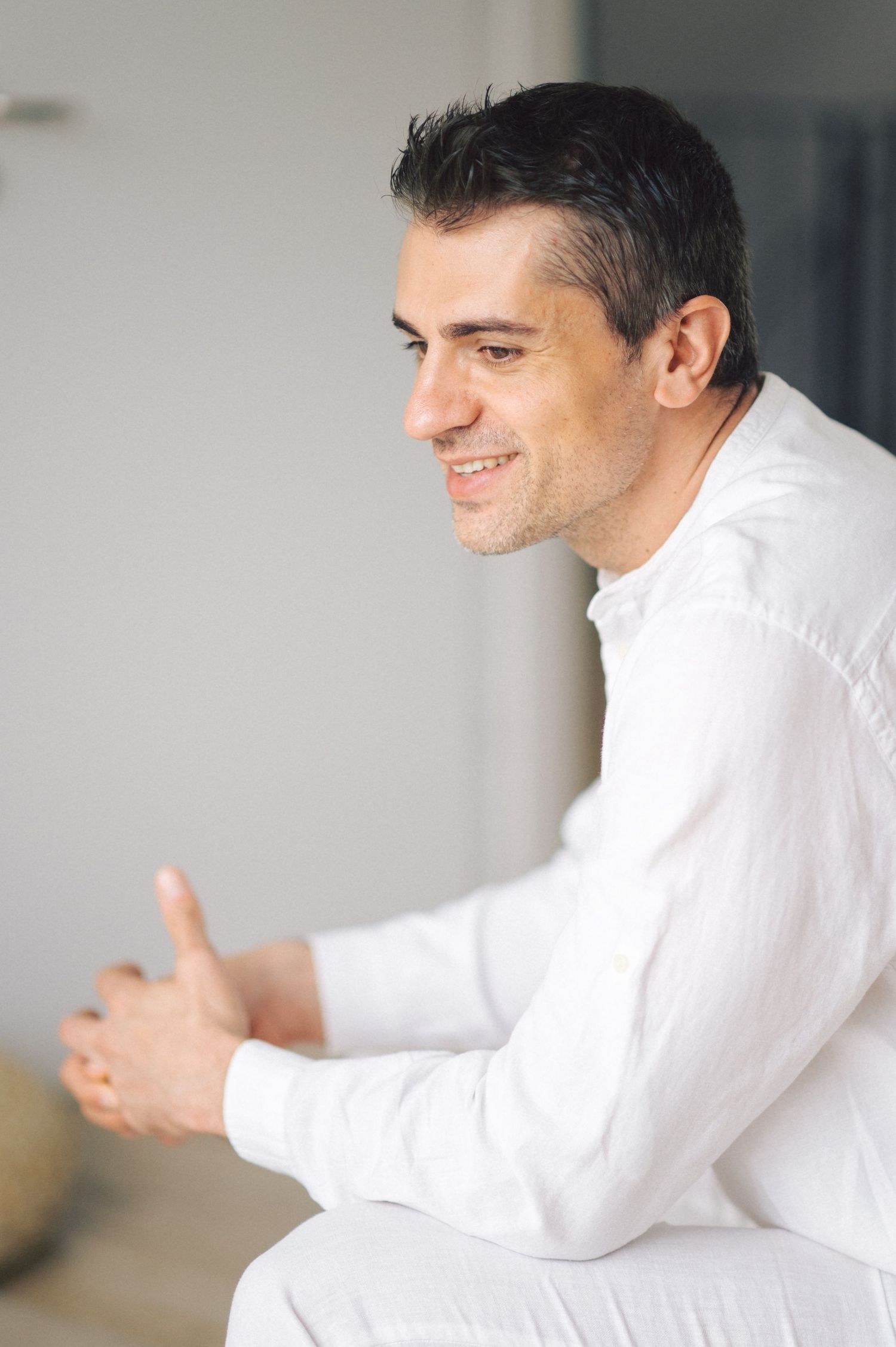 Professional wearing crisp white shirt sits in relaxed pose while gesturing with hands during conversation.