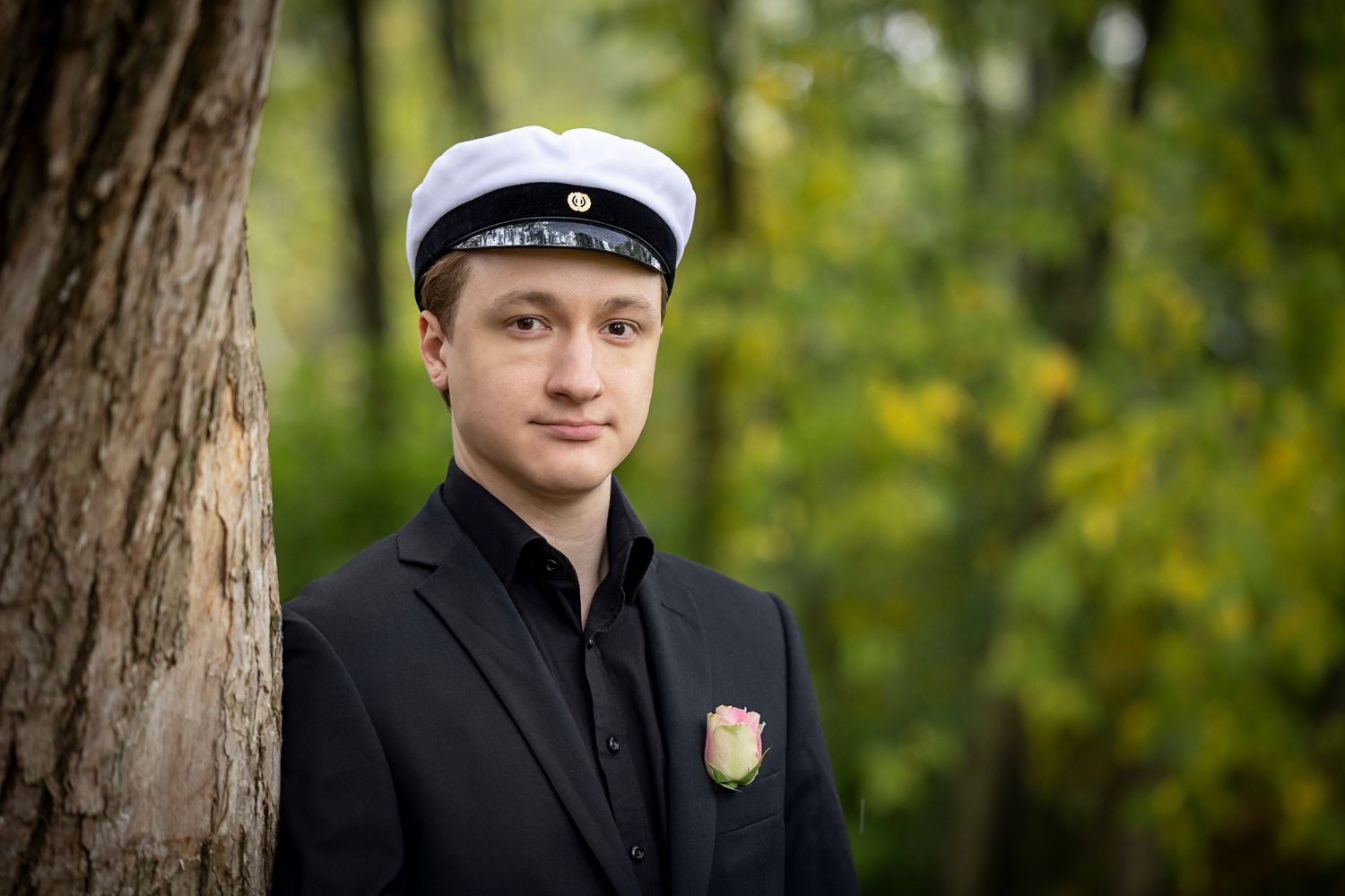 Mustaan pukeutunut ylioppilas nojaa terijoen salvaan.
