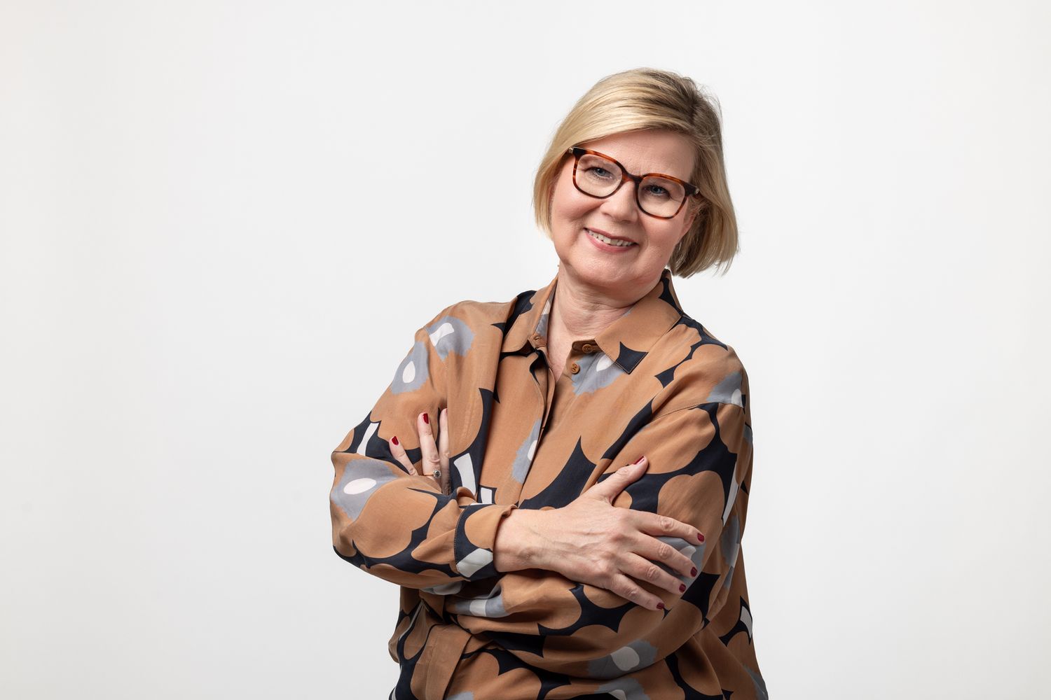 Unikkopaitaan pukeutunut nainen studiotaustan edessä.
